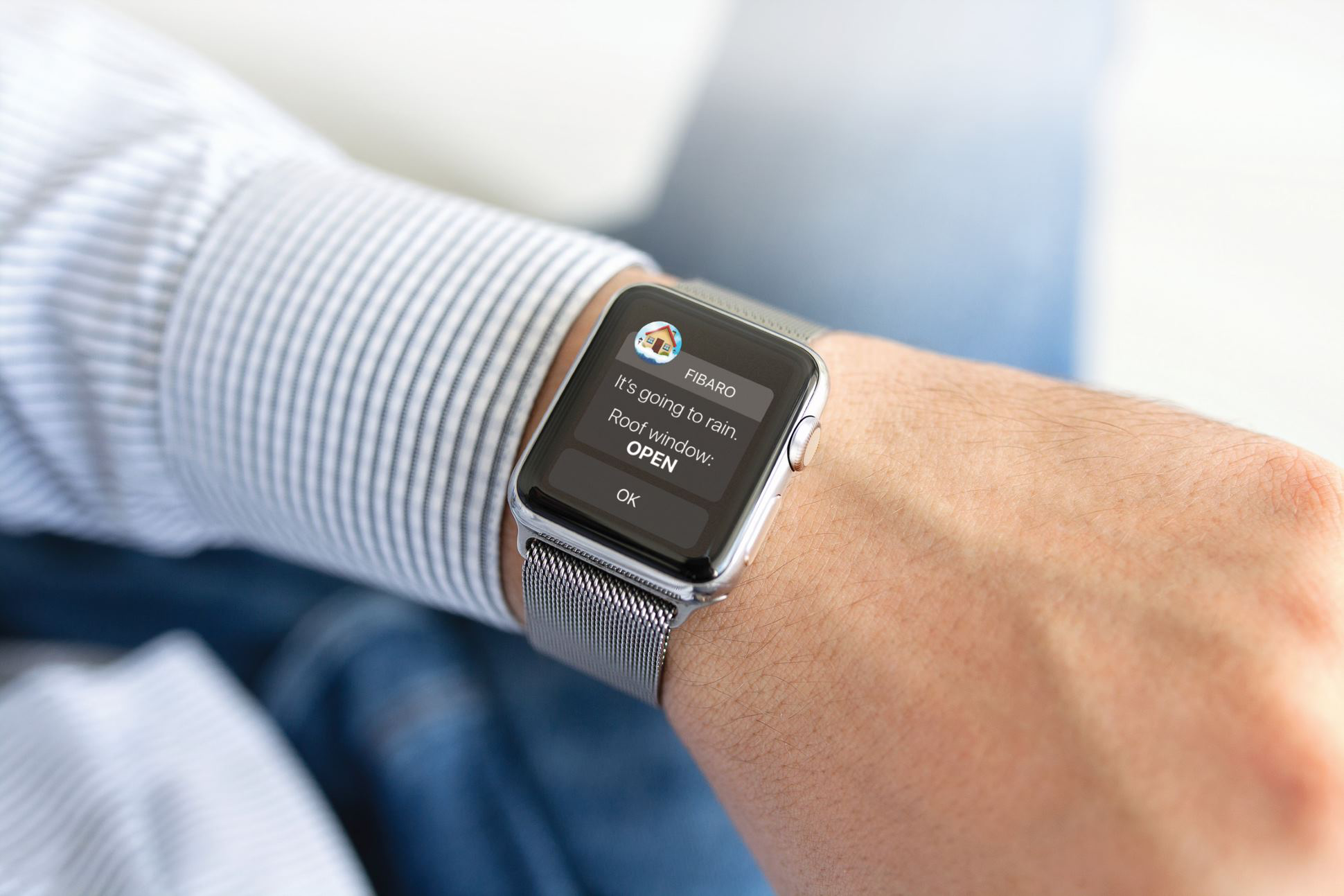A man wears a smart watch showing a notification from his home automation system. 